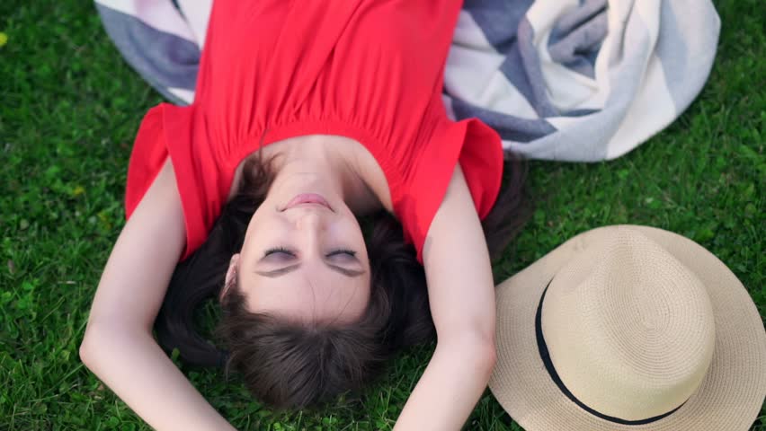 Relaxing in grass. Top view of beautiful young woman on the green grass