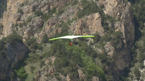 Green hangglider soar in the rocky mountains