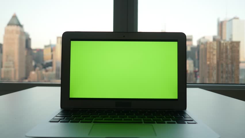 laptop computer with isolated green screen background. modern city office desk view. working at home. green chroma key background
