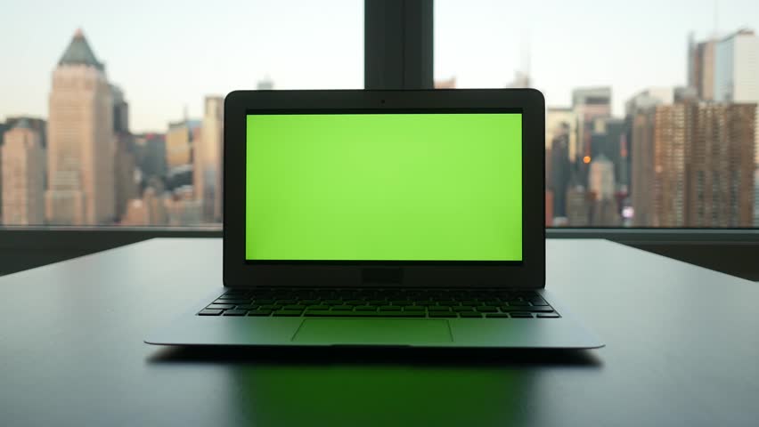 laptop computer with isolated green screen background. modern city office desk view. working at home. green chroma key background
