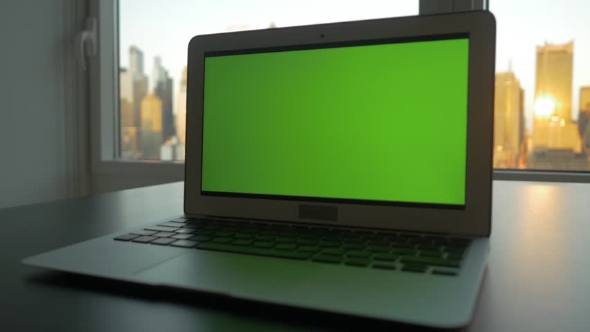 laptop computer with isolated green screen background. modern city office desk view. working at home. green chroma key background