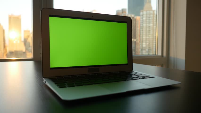 laptop computer with isolated green screen background. modern city office desk view. working at home. green chroma key background