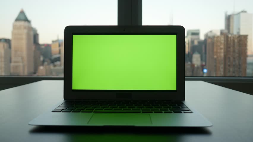 laptop computer with isolated green screen background. modern city office desk view. working at home. green chroma key background