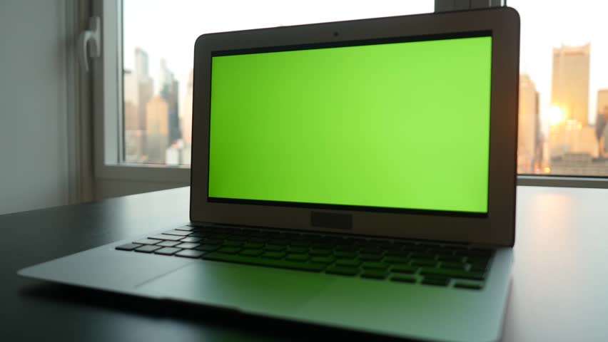 laptop computer with isolated green screen background. modern city office desk view. working at home. green chroma key background