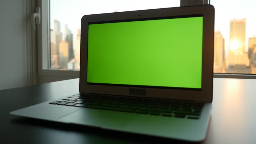 laptop computer with isolated green screen background. modern city office desk view. working at home. green chroma key background