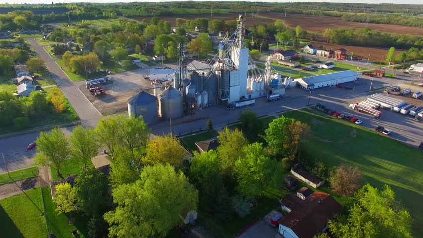 Scenic aerial flyover of midwest grain elevator, by early morning light.

