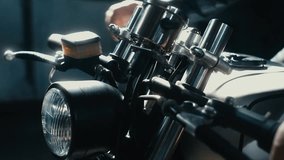 Close up shot of young Caucasian male biker in leather jacket driving his custom cafe racer motorcycle in large warehouse garage. 60 FPS slow motion Blackmagic URSA Mini RAW graded footage