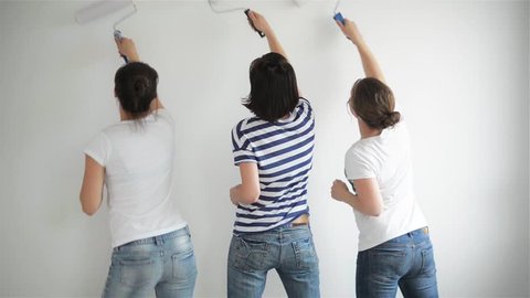 Friends makes repairs at home. Funny girls dance and paint the walls in the flat, good mood, making repairs and dance