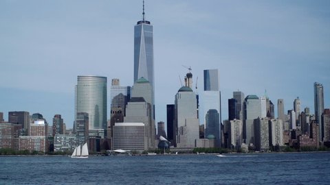 World Trade Center/Freedom Tower and Downtown New York City from the Hudson River in New Jersey, with Sailboat, motor boat, on a Sunny Day (medium shot, slow tilt up, 2016)