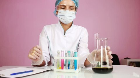 Female chemist comparing test tubes with chemicals. protective glasses