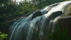 Continuous flow of white water over the mossy rock face of Prenn Waterfall. near Dalat. Vietnam. with sound. FullHD 1080p footage