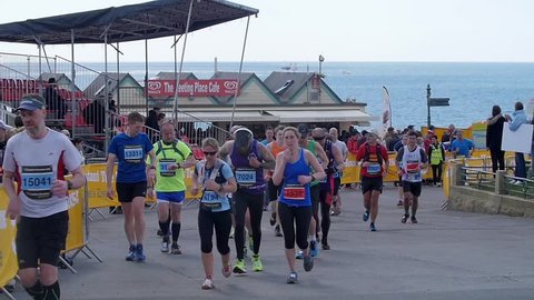 BRIGHTON, UNITED KINGDOM - APRIL 16, 2016 - Slow motion view of people running for the Brighton marathon with the sea in the background