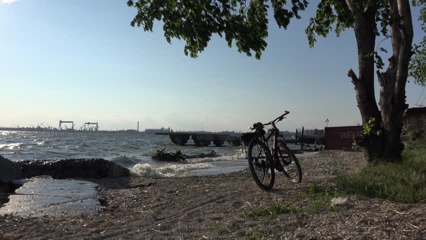 Bike standing on riverbank with large waves, storm sontrast at sunset