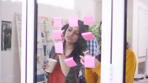4K Creative business group in modern office, brainstorming for ideas with sticky notes. Shot on RED Epic. UK - April, 2016