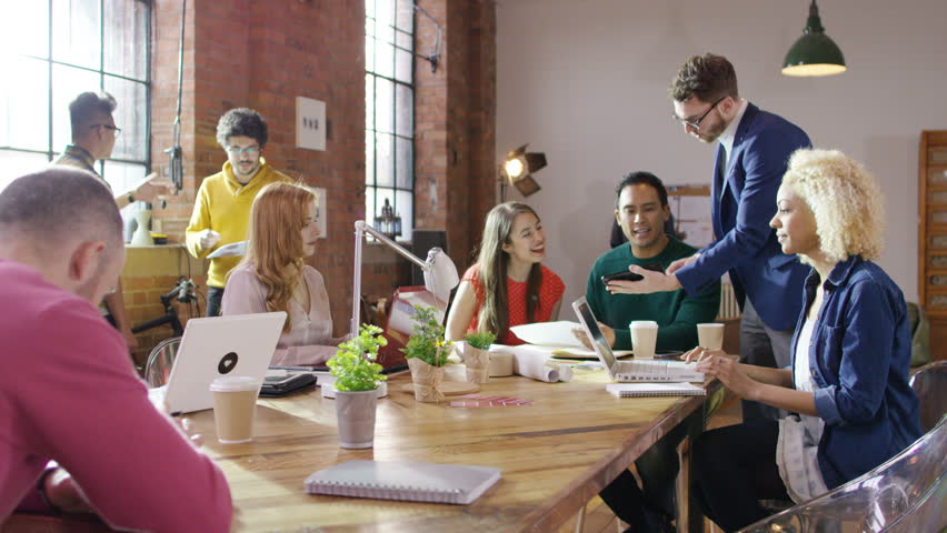 4K Portrait of cheerful hipster businessman working with colleagues in loft office. Shot on RED Epic. UK - April, 2016