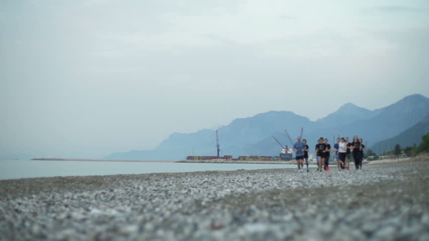 group of sportsmen jogging along the sea slow motion