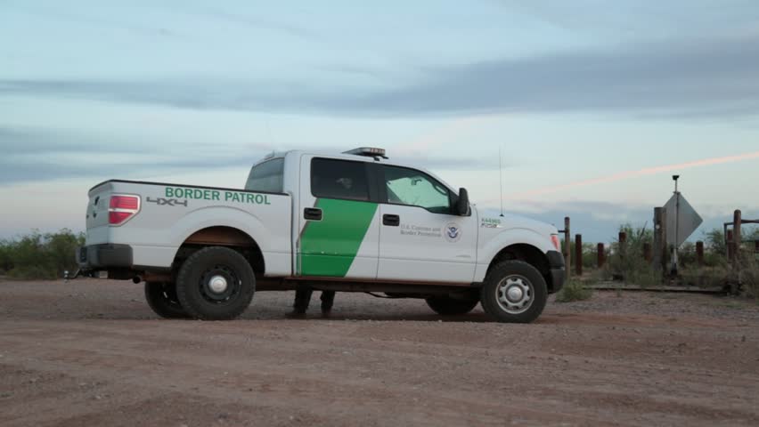 Border patrol vehicle parked beside a fence in the desert 