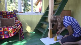 young woman paint wooden column with yellow colour in country home terrace. 4K UHD video clip.