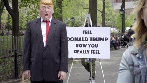 NEW YORK - MAY 15, 2016: "tell Donald Trump how you really feel" sign with masked impersonator in Park in NYC. Washington Square Park is the scene of much street art and performance in the city.