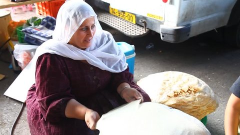 ISRAEL - NOV 6, 2010: A mother and daughter bake pita bread on hot plates on November 6, 2010 in Israel.