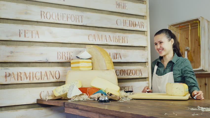 Friendly seller communicates with the buyer. The cheese shop