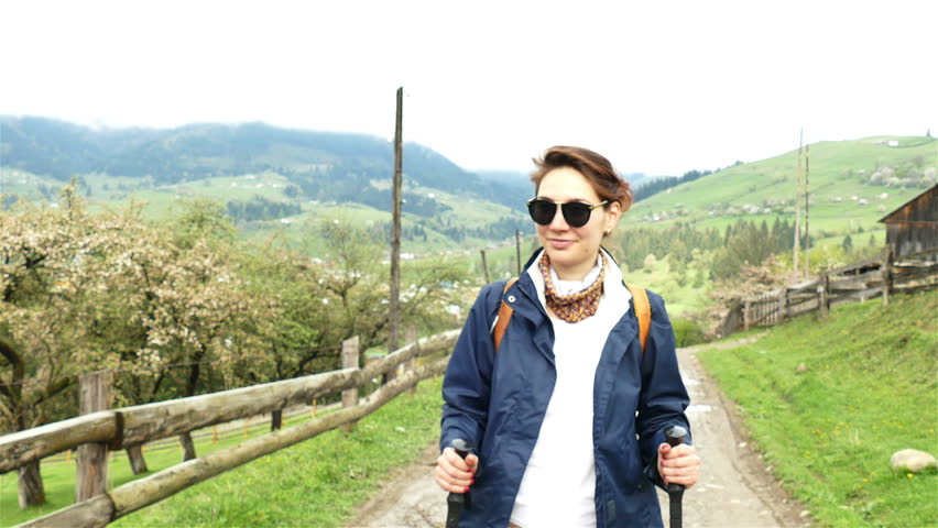 
4K. Attractive girl  hiker  tourist with backpack  goes up  in  mountain village
