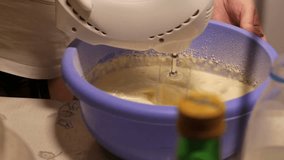 Female hands working with a mixer and add the milk to the mix. Video full hd.
