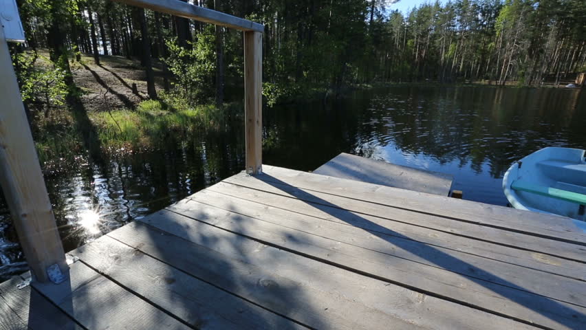 Wooden bridge overlooking lake ripples against the green wood. Static video full hd.