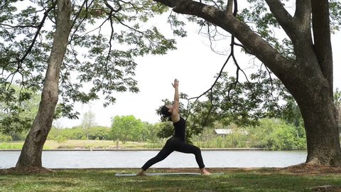 Asian woman wearing in black outfit doing yoga in the park