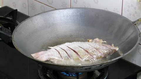 Frying Snapper fish in pan with vegetable oil.