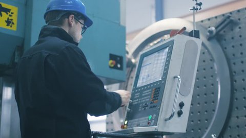 Factory worker is programming a CNC milling machine with a tablet computer. Shot on RED Cinema Camera.