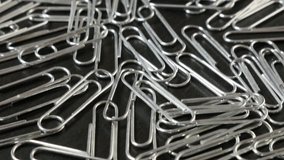 Metal paper clips on office wooden table close-up slow tilt 4K 2160p 30fps UltraHD footage - Steel wire paperclips with looped shape 4K 3840X2160 UHD tilting video