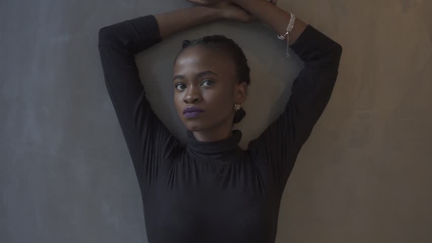 Portrait of beautiful african american model in elegant black dress on dark studio background