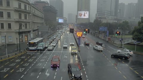 SHANGHAI CIRCA 2013: Downtown people's square main street in the rain. Hazy polluted Tibet rd or Xizang rd in rainy weather. Busy traffic intersection in China with bright billboard signs.