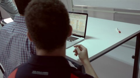 2 Shots: Businessmen around laptop view data on screen. Three men sitting around a laptop analyze data in a spreadsheet.