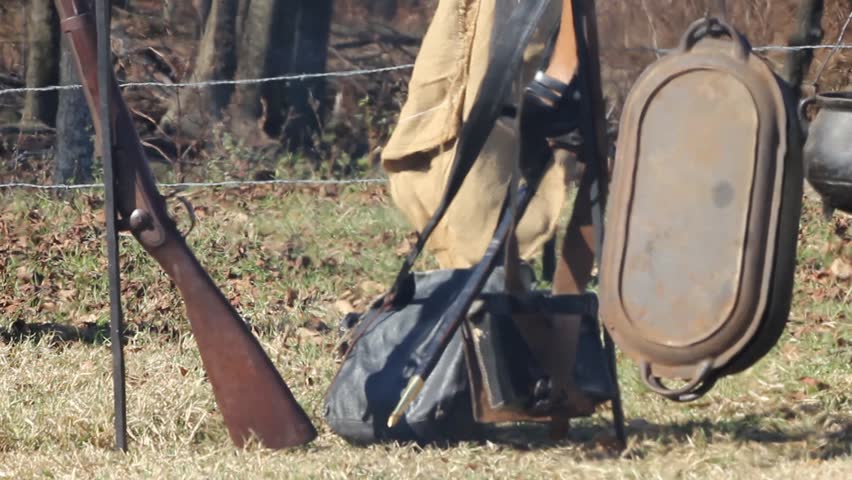 Smoke and embers in front of civil war era rifle and camping equipment