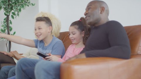 4K Happy family watching TV on the couch at home UK - April, 2016
