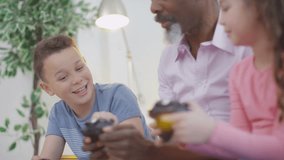4K Happy grandfather trying to learn to play video games with grandchildren UK - April, 2016