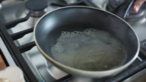 Barcelona, Spain - November 11, 2012: Woman swirling boiling water in pan over stovetop