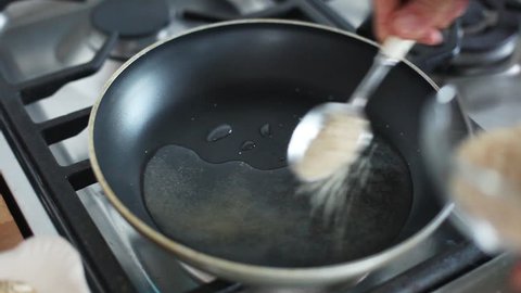 Barcelona, Spain - November 11, 2012: Woman putting water and sugar in frying pan on stovetop