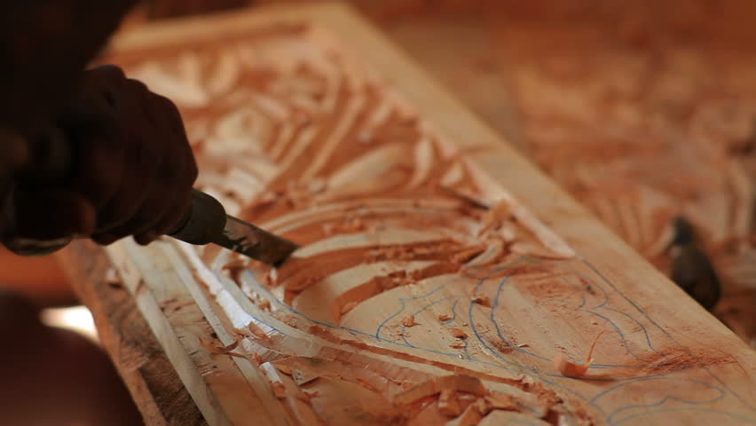 Close up of man chiseling designs out of wood in Kenya, Africa.