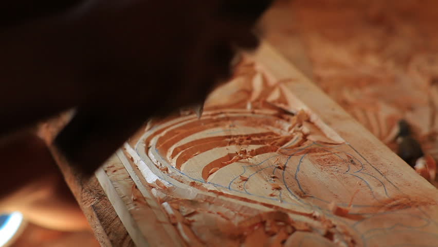 Close up of man chiseling designs out of wood in Kenya, Africa.
