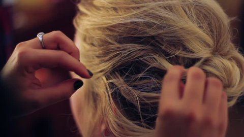 Hair stylist inserting bobby pins into a woman's hair