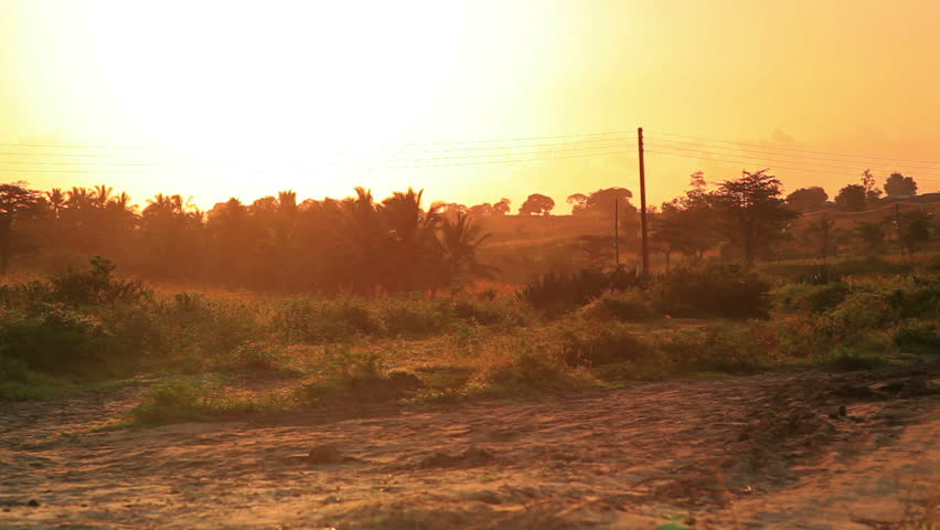 A girl walking off in the distance as the sun is coming up.