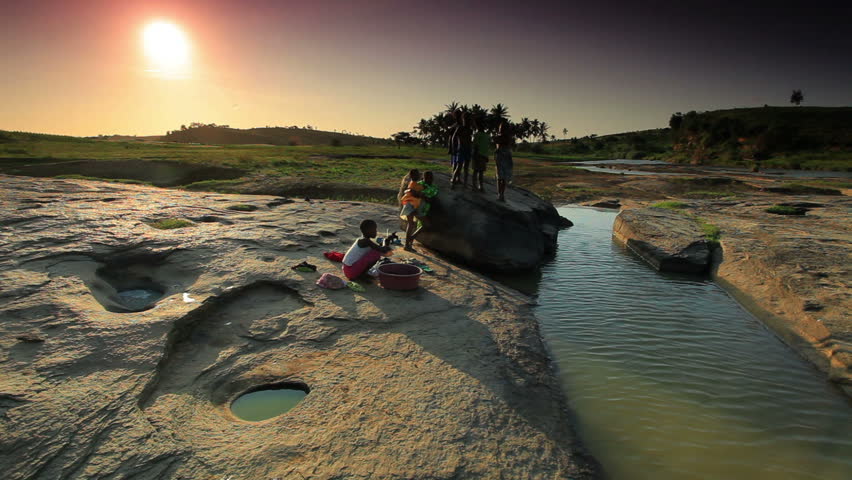 KENYA, AFRICA - CIRCA AUGUST 2010: Kids wash clothes in river under sunset in
