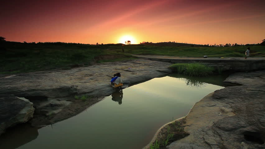 An african woman washes her child at a river near a village in Kenya two hours