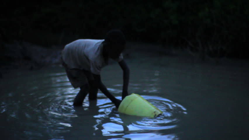 KENYA, AFRICA - CIRCA AUGUST 2010: Boy uses bucket to collect water from water