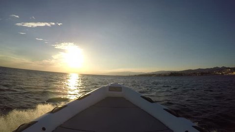 Bow of a rubber boat navigating fast at the sunset close to the Italian coast
