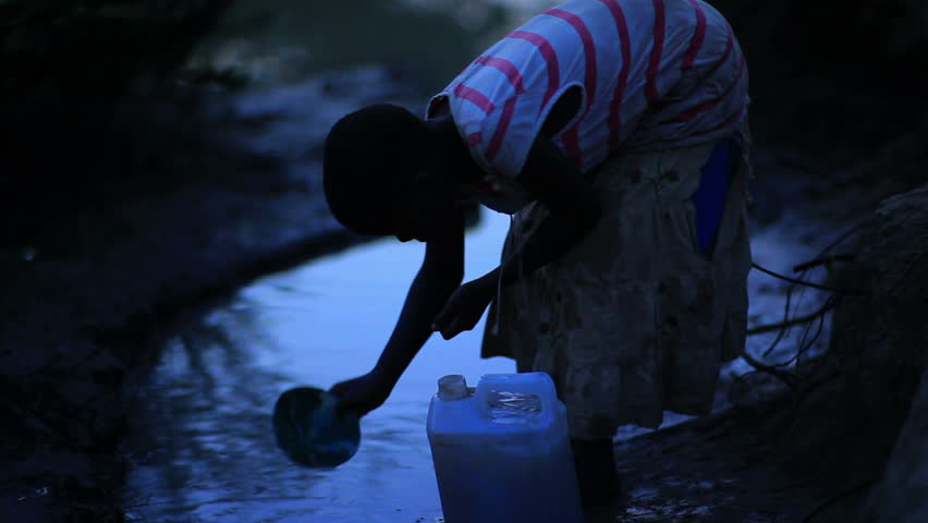 KENYA, AFRICA - CIRCA AUGUST 2010: A girl fills a water bucket at a watering