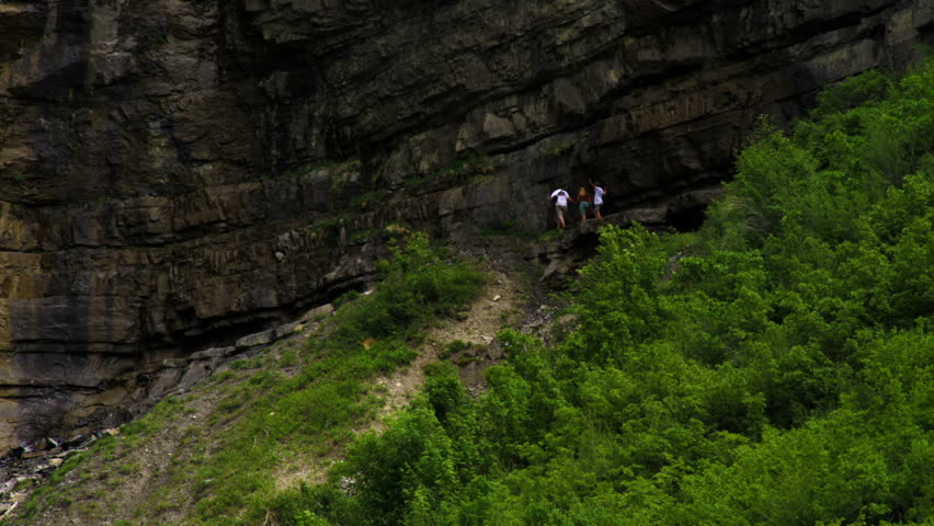 Three people walking along the base of a cliff near Bridal Veil Falls in Provo